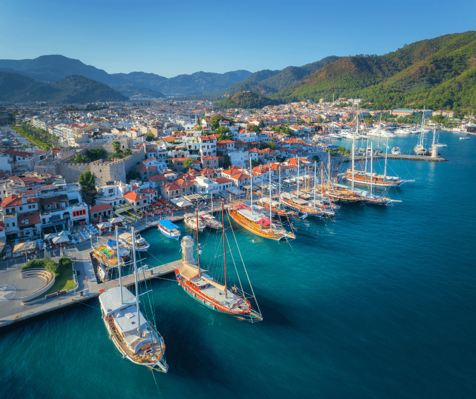 Segeltörn Türkei - Marmaris von obenm Stadt mit weißen Häusern, Burg, Guletsm Segelboote, Katamarane auf dem türkisfarbenen Meer, grüne Berglandschaft im Hintergrund