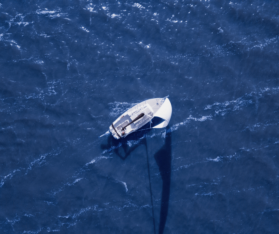 Weißes Segelboot welches durch das blaue Meer navigiert