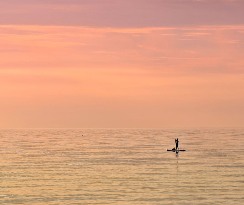 Stand-up Paddle Boarder auf einem See bei Sonnenuntergang.