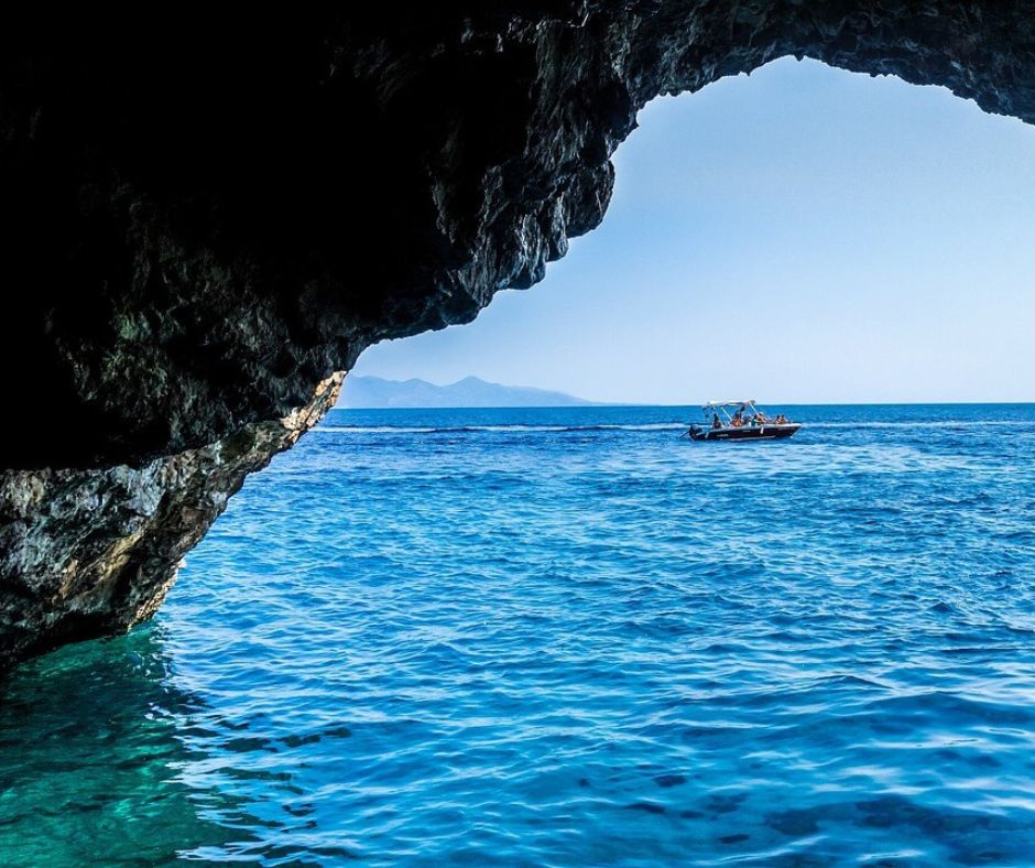 Höhlenausgang auf dem Meer. Im Hintergrund sieht man ein kleines Motorboot.