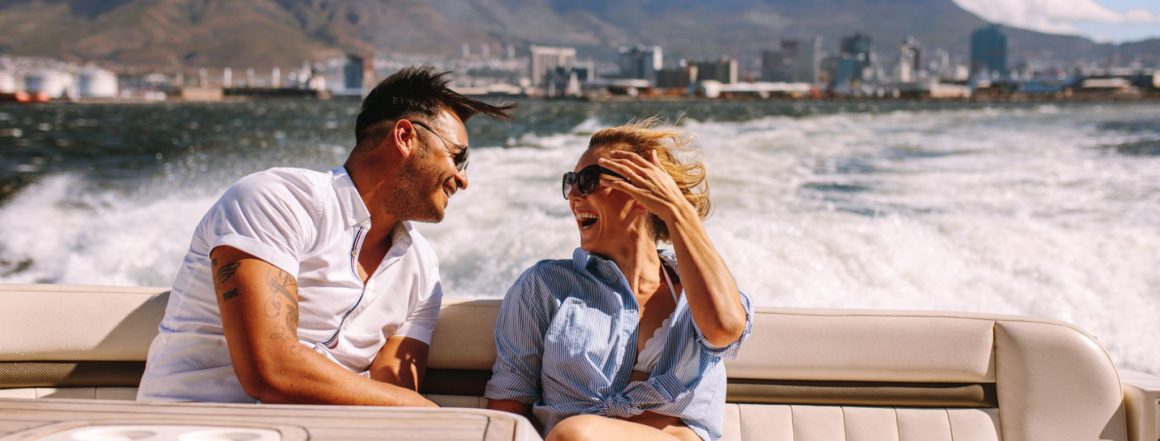 Ein Mann und eine Frau auf einem Boot. Im Hintergrund sieht man die Wellen und Berge.