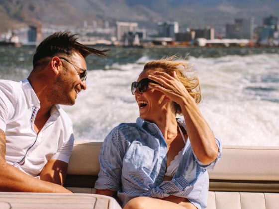 Ein Mann und eine Frau auf einem Boot. Im Hintergrund sieht man die Wellen und Berge.