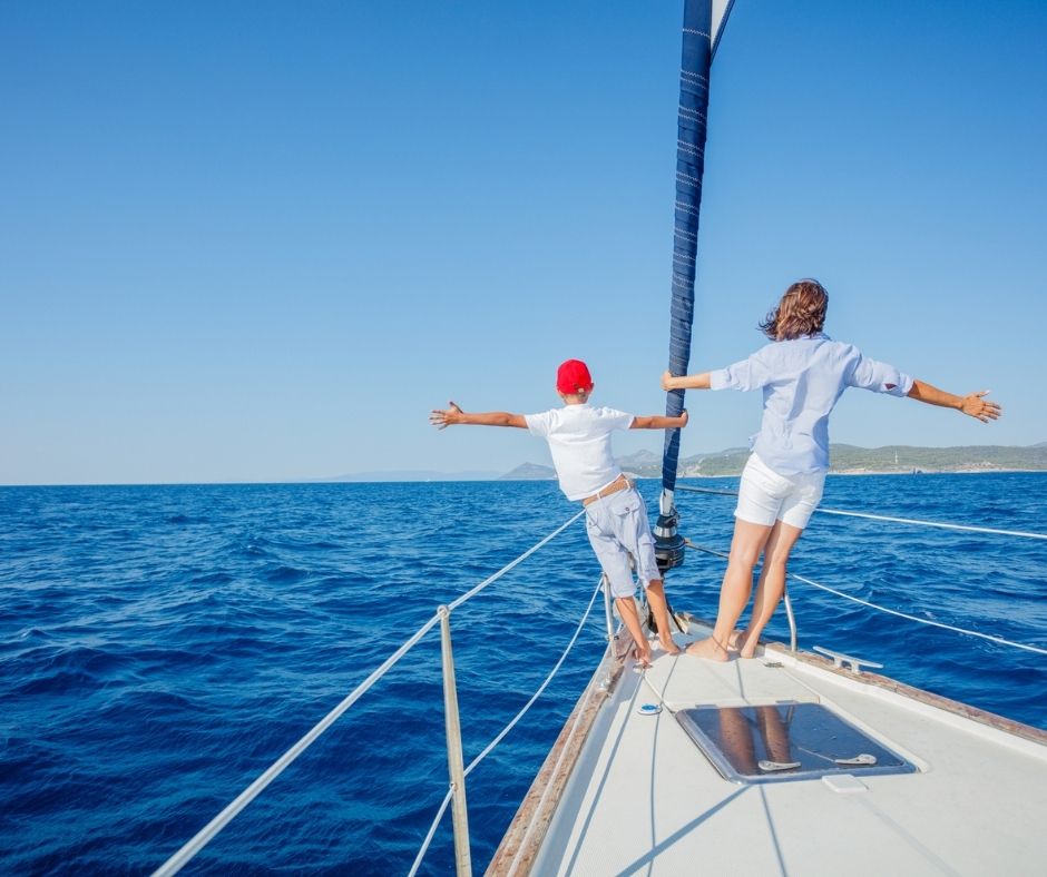 Madre e figlio che si divertono su una barca a vela. con le mani in alto