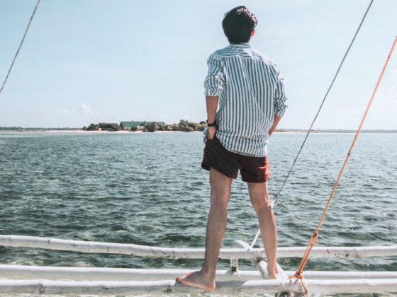 uomo di spalle in piedi su una barca che osserva l'orizzone