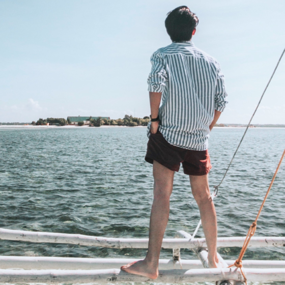 uomo di spalle in piedi su una barca che osserva l'orizzone