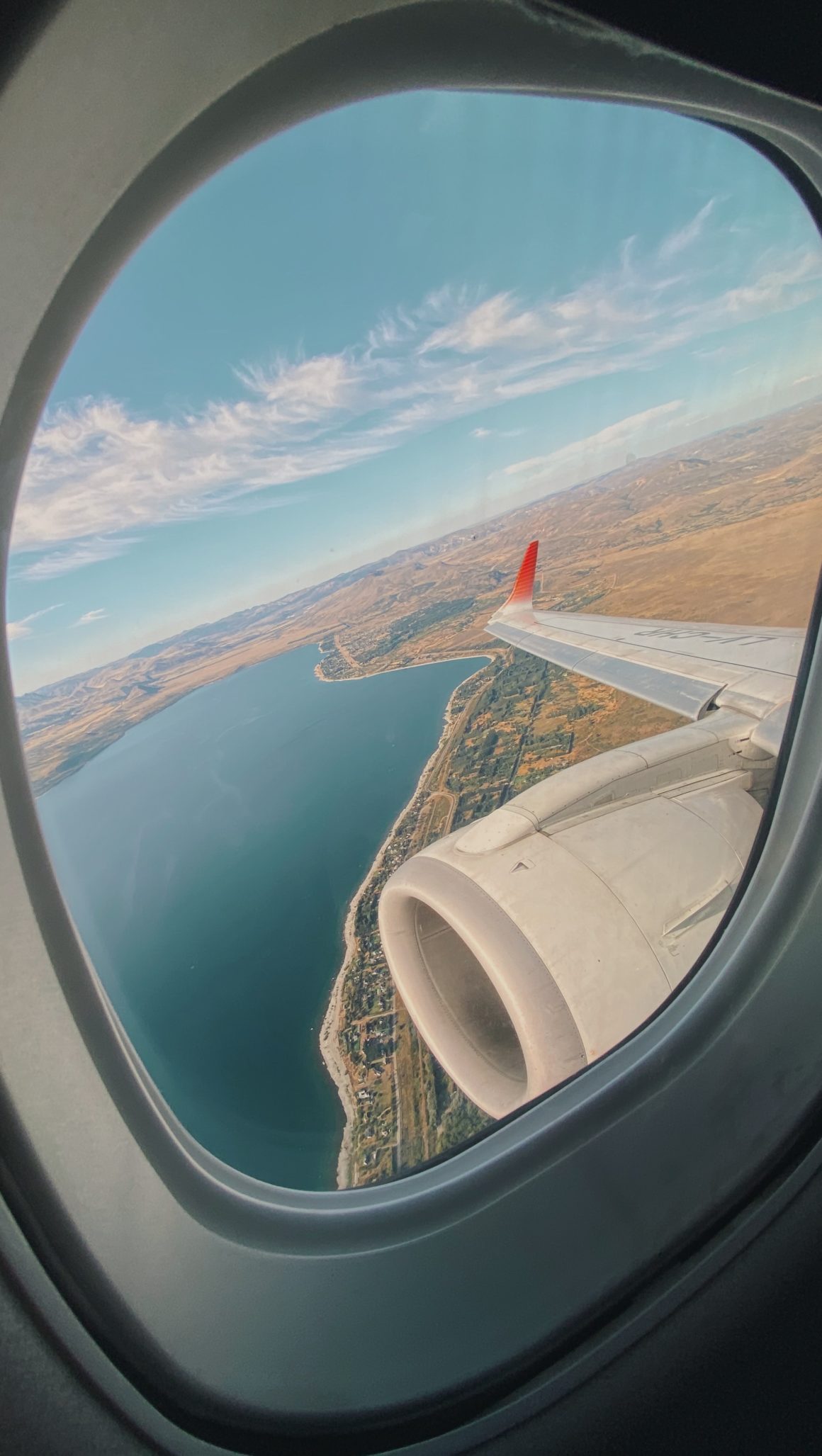 raam van een vliegtuig met uitzicht op de zee