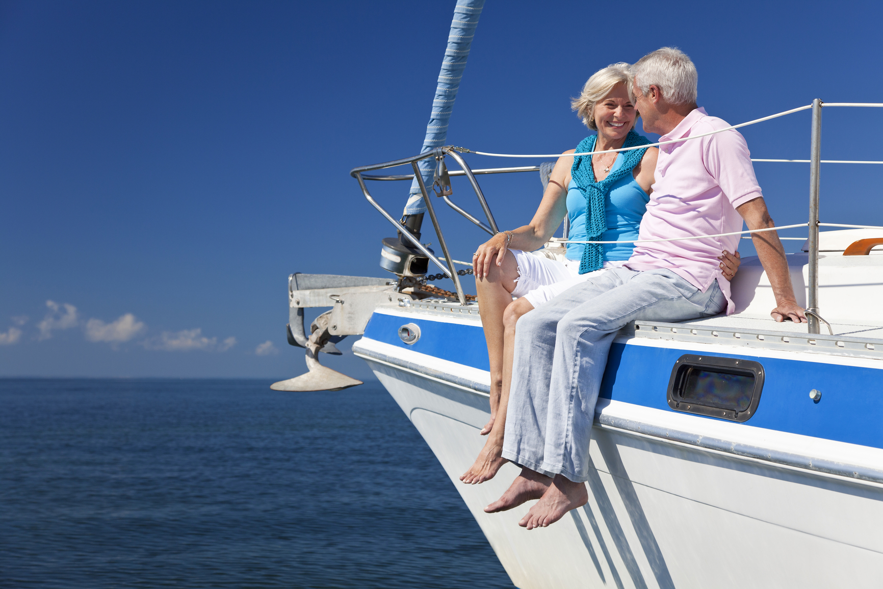 A happy senior couple sitting on the deck of a sail boat on a calm blue sea in the Ionian Islands