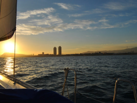 View of Barcelona skyline from a boat across the sea during sunset