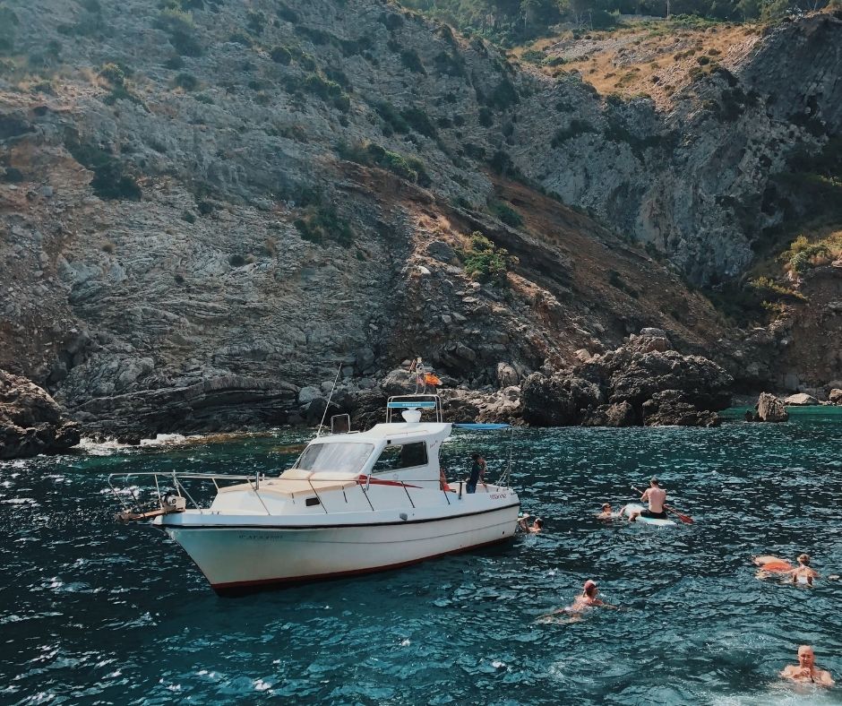 boat sailing through the bay of Mallorca with people swimming nearby