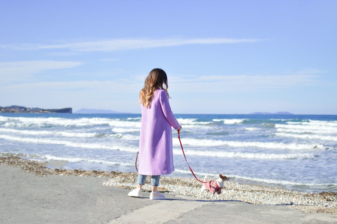 Woman walking dog off on Acharavi Beach in Corfu