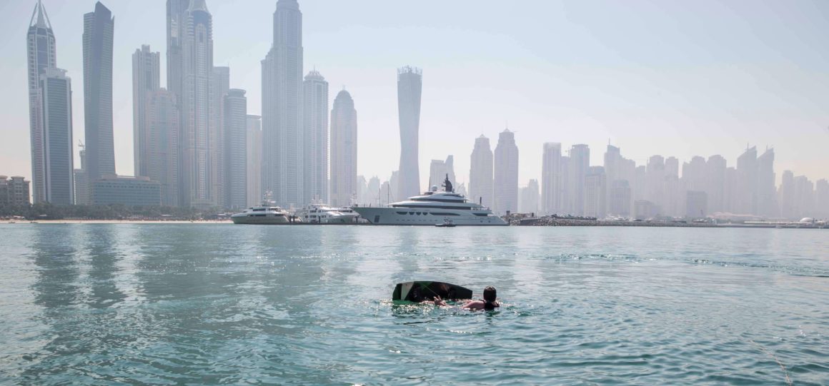 A view of the Dubai skyline with yachts and a wakeboarder