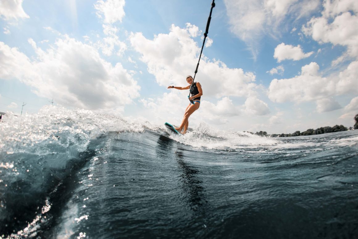 A person wakeboarding on a wave from a wakeboard boat