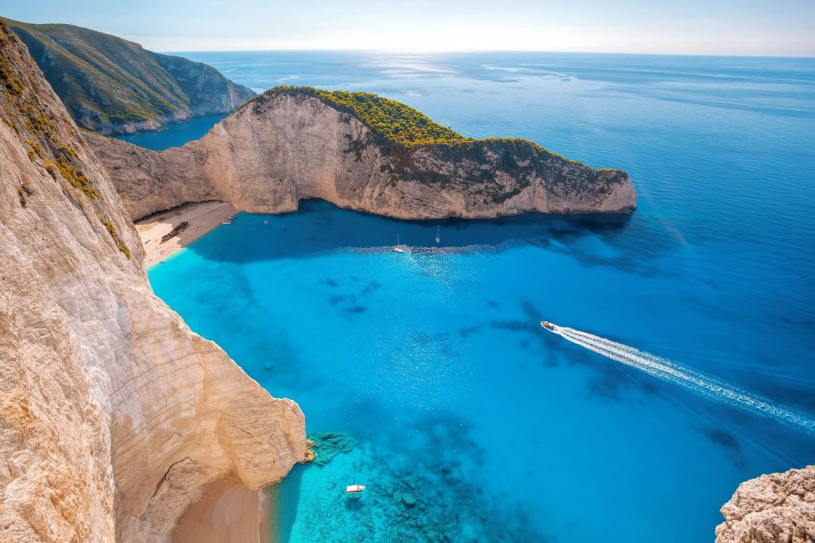 View of the cliffs and a boat in the bright blue water of Zakynthos, Greece