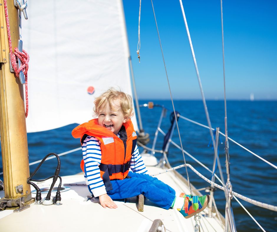 Small child wearing a life jacket sitting on the front of a boat